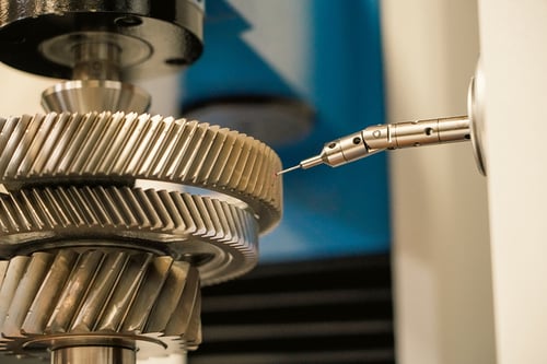 Inspecting a gear with a coordinate measuring machine (CMM) after grinding to ensure specifications are met. 
