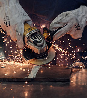 Right angle grinder with grinding wheel on a metal workpiece. 